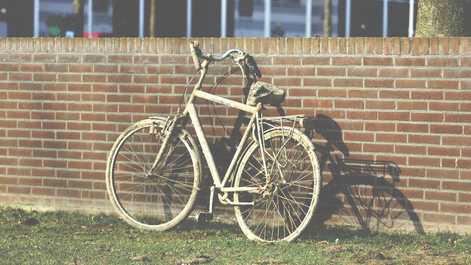 An old mud-caked city bike leaning against a brick wall