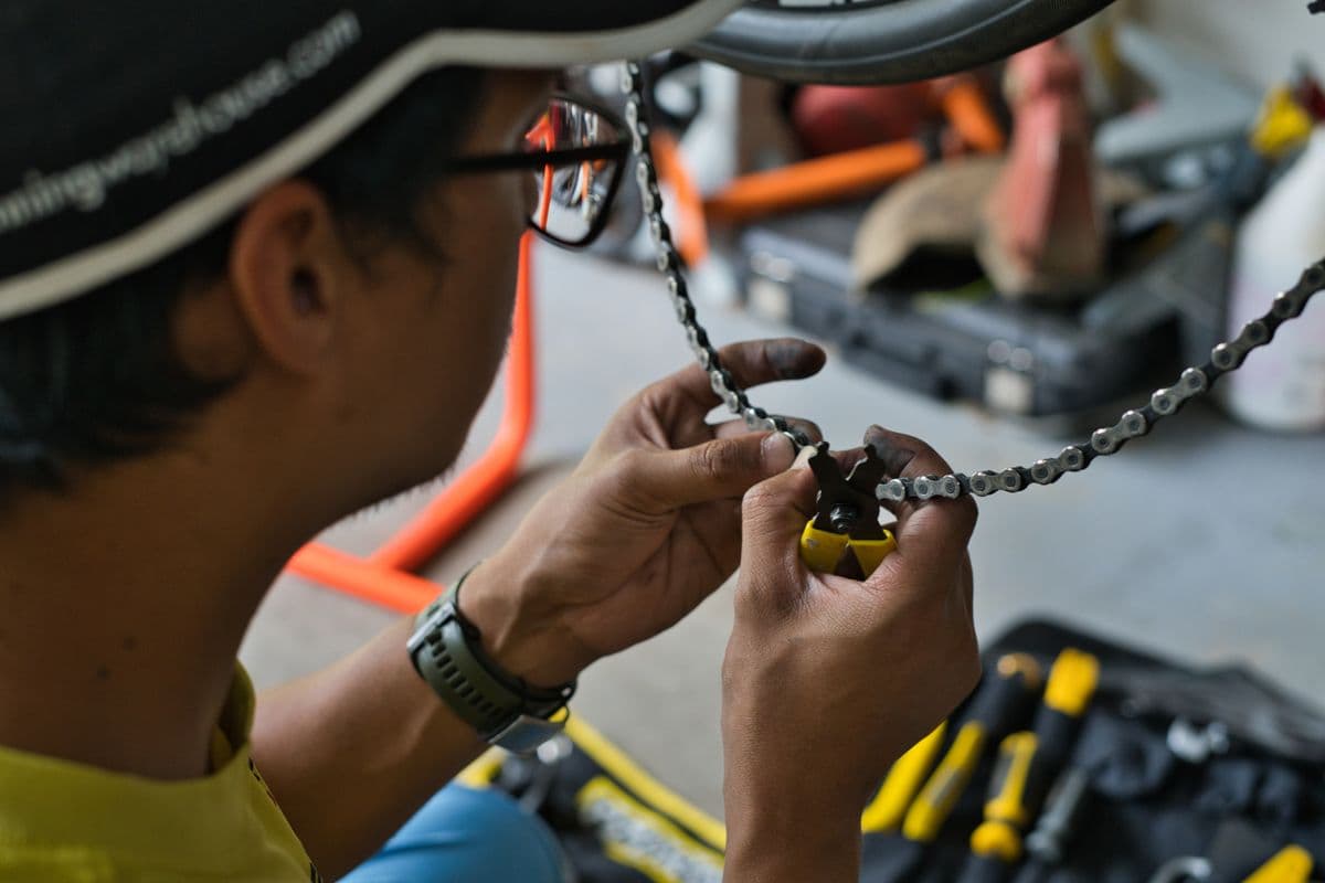 A mechanic joining a chain with a chain tool at the workbench