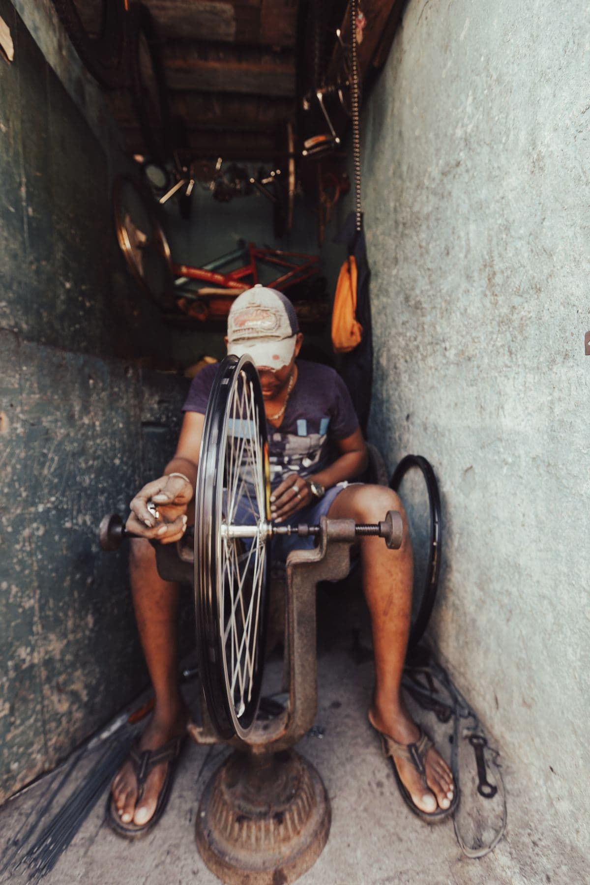 A craftsman truing a bicycle wheel on a vintage truing stand