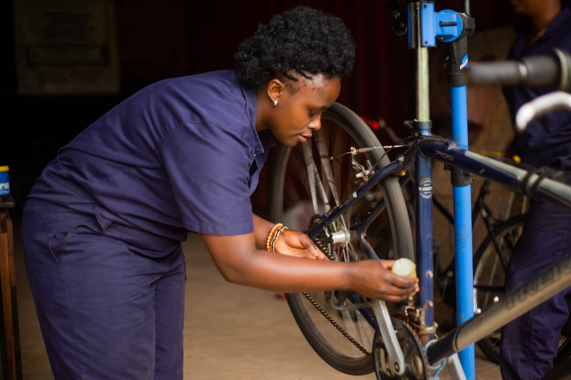 A mechanic in coveralls working on a road bike clamped in a repair stand